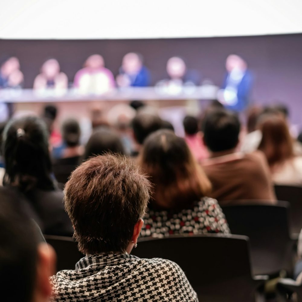 Rear view of Audience in the conference hall or seminar meeting which have Speakers